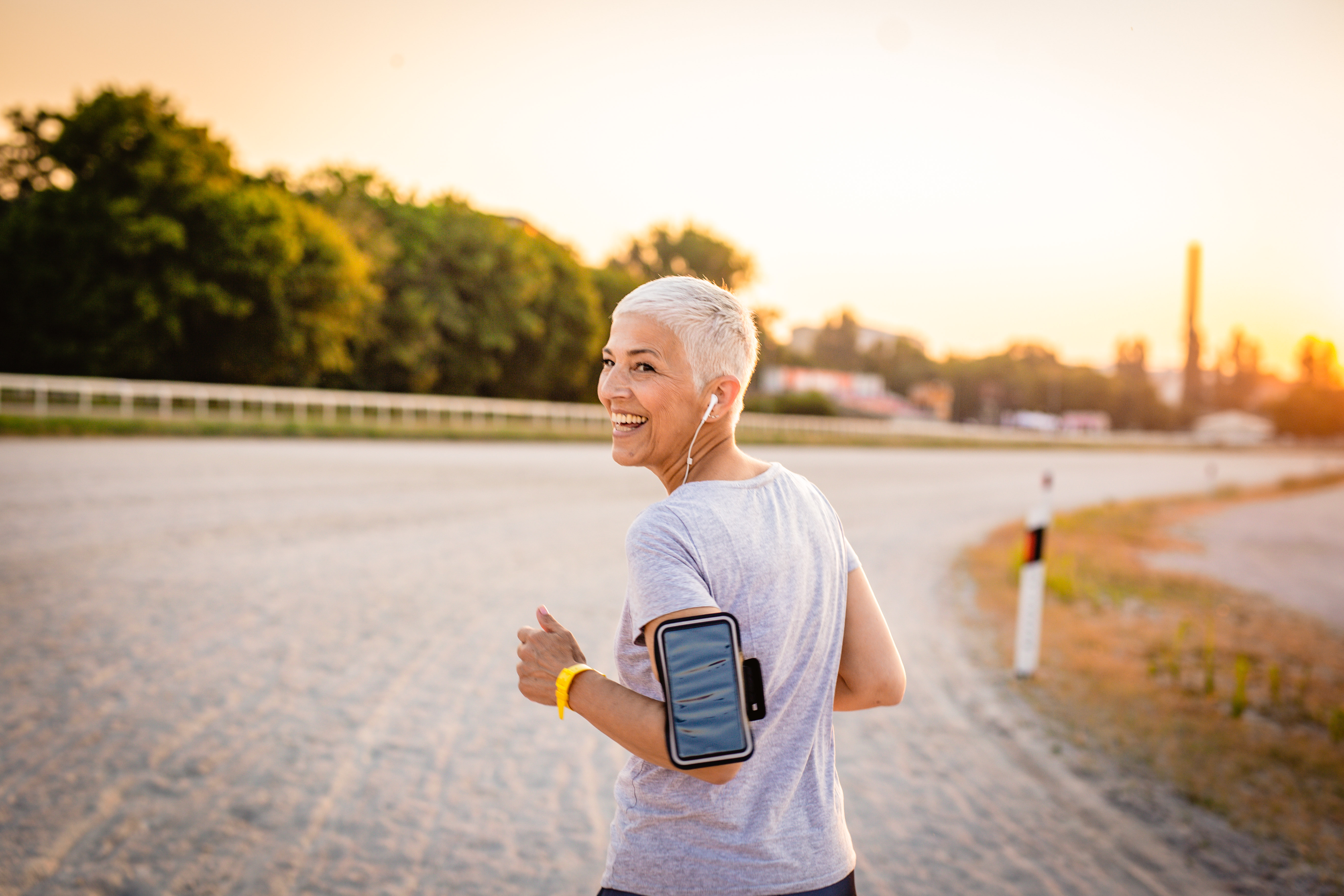 A person with medium-light skin tone and bleached white hair, running with her headphones on, on a track outdoors.
